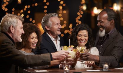 group of middle aged friends celebrating in bar together